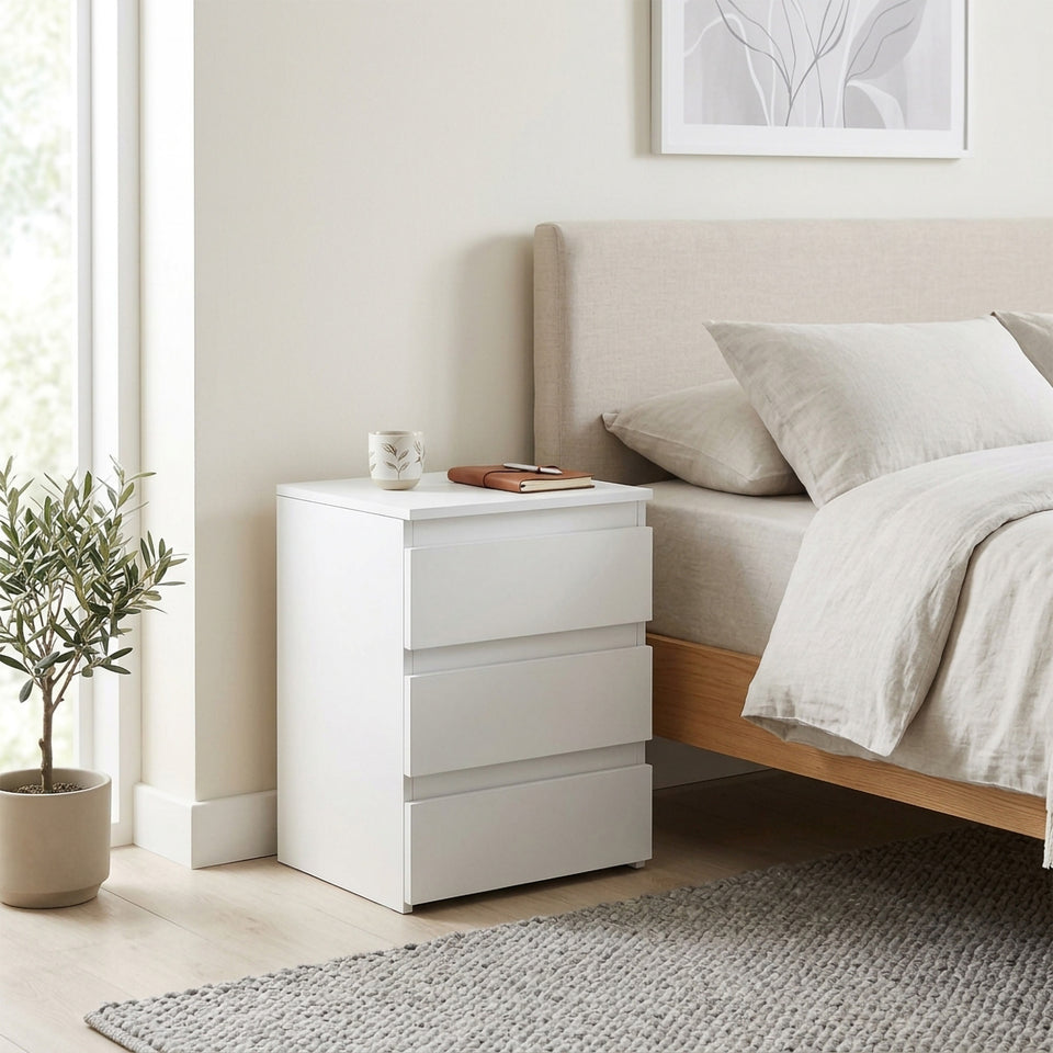 White LORA bedside table with 3 drawers beside the bed