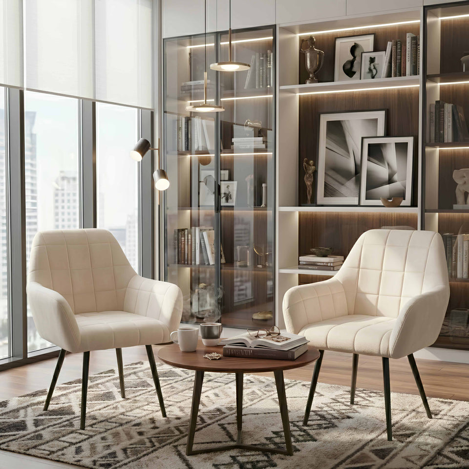 Modern living room with two cream chairs, a coffee table, and a bookshelf.
