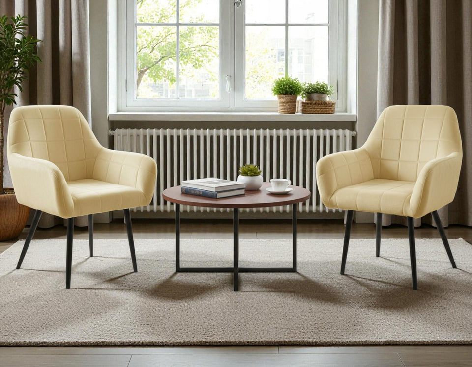 Two beige armchairs with a small round table in a room with large windows and curtains.